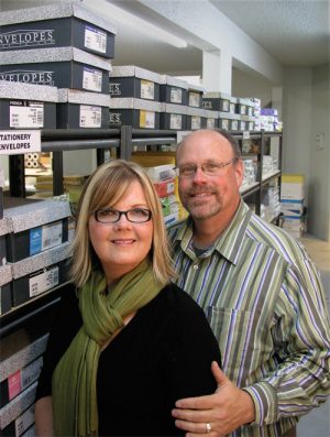 A man and woman standing in front of shelves.
